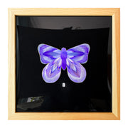 Illustration on cut out paper of a lavender butterfly with abstract striations on its swings, looking loosely psychedelic. Butterfly is mounted on black paper and in a light grain wooden frame. 