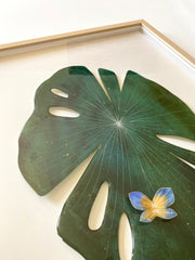 Painted cut out lily pad leaf coated in resin, dark green with subtle marbling pattern and thin white stripes. A small blue and yellow butterfly rests atop the leaf.  Displayed at an angle to show sheen.