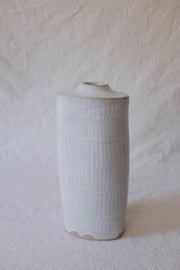 Ceramic vase with small opening and very faint gray lines.