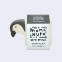 Small off white planters with a semi flat penguin head coming out of one side. It is wrapped in product packaging, which shows what plant seeds are included. (Mild Chamomile)