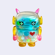Pastel rainbow colored soft vinyl figure with colorful round beads inside. Figure is shaped like a smaller Big Boss Robot, with a bigger head than normal and two black eyes with sparkles as pupils. A red heart is on its upper right chest.