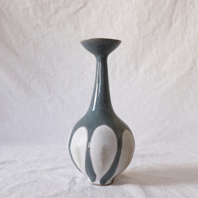 Vase with very skinny neck and slightly fluted top. Bottom of vase is white, top is bluish gray with dripping look.