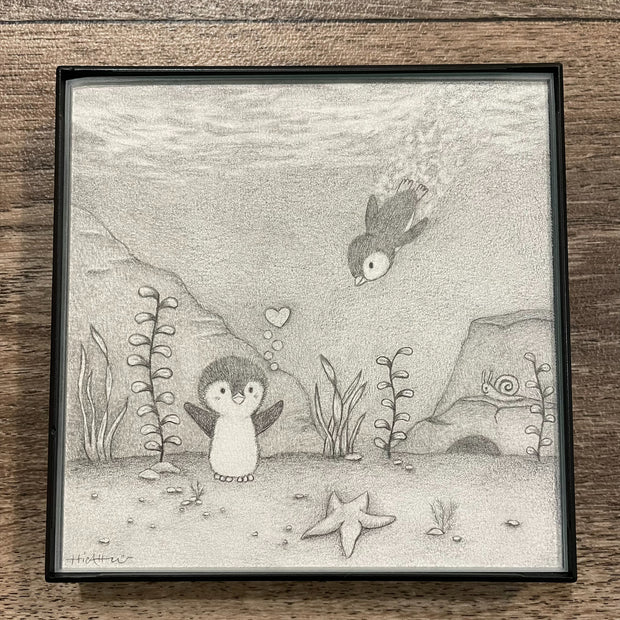 Graphite drawing of a small penguin standing underwater, with a heart bubble coming up from it. Another penguin swims down towards the other. Piece is in thin black frame.
