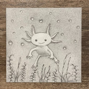Graphite drawing of an axolotl, floating in water with bubbles and a heart shaped bubble directly above it. Sea weed frames the bottom of the piece.