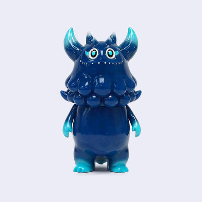 Vinyl figure of a dark blue monster, with a chubby body and small arms and legs. its head looks like an octopus, with horns and wide eyes.