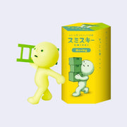 A small plastic character, light green with a circular head and human like body. It walks purposefully and holds a ladder over its shoulder. It stands next to its product packaging.