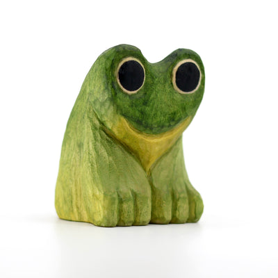 Small whittled wooden sculpture of a green frog with very large eyes, mostly large black circles with a thin yellow outline.
