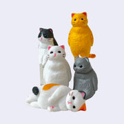 5 figures of chubby, fluffy plastic cats of different colors, all staring off into the distance as if zoning out. Some stand on hind legs, others sit and one lays on the floor.