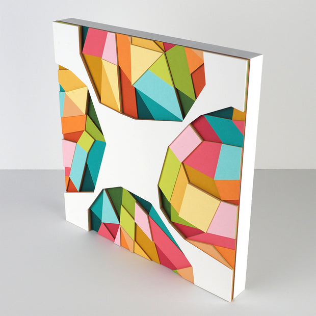 White paper with 4 colorful geometric shapes on each side of the sheet, made up of layers of colorful paper assembled into a larger geometric shape. Shown at the side to display 3 dimensionality