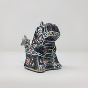 Side view of a small sculpture of a primarily black Godzilla, with peeks of rainbow color coming out in place. It has many white lines depicting various robotic elements.