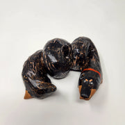 Sculpture of a black dachshund with brown underbelly and paws, its body an extended coil like a slinky. It has a red collar.