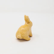 Yellow ceramic bunny with no facial features.