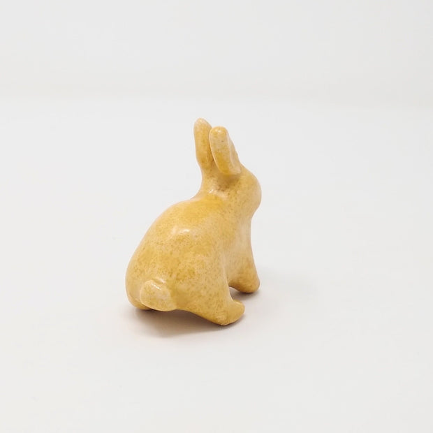Yellow ceramic bunny with no facial features.