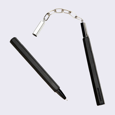 Black pen with a chain attached to its cap, which connects it to another pen such as a nunchuck.