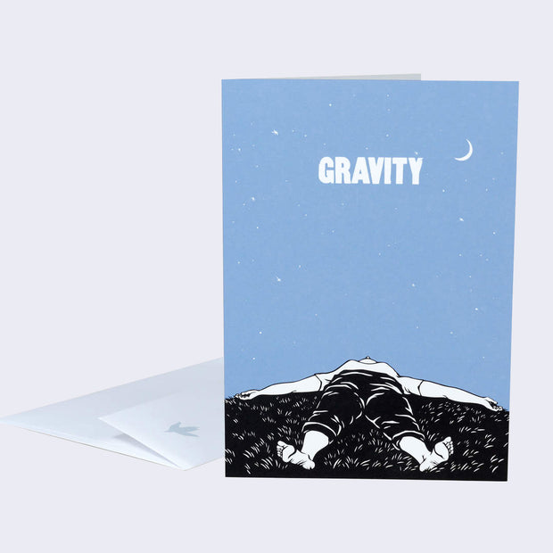 The front of a note card is shown. The card has an illustration of a person laying on grass with the vast sky above. Text above says gravity.