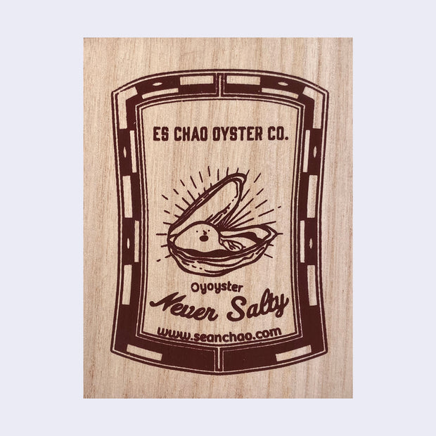 Wooden rectangle box with a patterned border, within text reads "ES Chao Oyster Co." in all caps over an illustration of a happy oyster popping out of its shell. "Oyoyster Never Salty" is written below illustration.