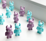 A window sill with many Big Boss Uamou figures, alternating between sea foam blue-green colored and a mauve purple.