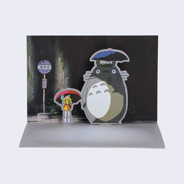 Example of pop up notecard, featuring a scene of Totoro and a young girl standing at the bus stop in the rain. The pair are popped up out of the background, creating 3 dimensionality. 
