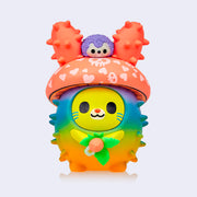 Vinyl figure of a bunny with a rainbow colored round, spiked body like a cacti. Its head is a mushroom cap with a small purple hedgehog on its head.