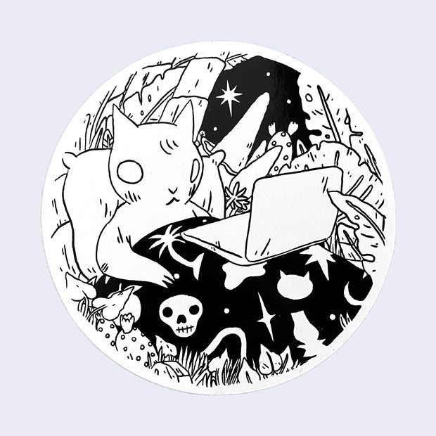 White circle sticker with a drawing of a cat in bed using a laptop. The cat's blanket has a skull and other mystical motifs.