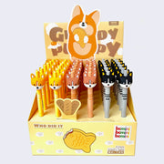 Yellow cardboard pen display, with a large illustration of a chubby corgi holding a taiyaki with "Greedy Puppy" written behind it. It displays 36 pens with simplified corgi heads as pen toppers.