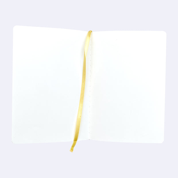 Open spread of blank sketchbook pages, with a yellow place marker ribbon running down the center.