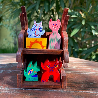Wooden two story shelf with 5 small painted wooden figures, including funky heads and little devils.
