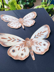 Close up of two brown moths made out of paper, shown at the side to display 3 dimensionality.
