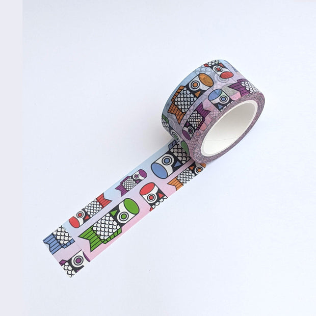 Washi tape rolled out to display pattern of blue to pink ombre tape with different color and sized cartoon fish flags. Colors include green, red, purple, blue and orange.