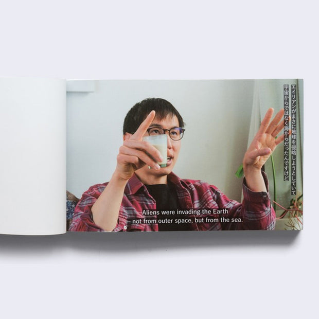Single book page, displaying a full bleed photo of Patrick Tsai with his hands up in explanation. "Aliens were invading the Earth not from outer space, but from the sea." is written under him in TV caption style text.