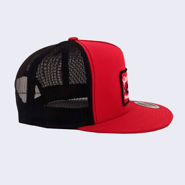 Side view of red baseball cap with rectangle patch. The back of baseball cap is all black mesh.