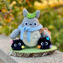 Knit sculptural dolls - one of a fluffy gray character with a leaf atop its head and 2 fluffy black sprites with colorful stars on themselves