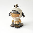 A ceramic sculpture of a girl wearing a hooded mini dress with dog ears. Atop her head is a small dog, matching colors with her outfit.