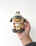 A ceramic sculpture of a girl wearing a hooded mini dress with dog ears. Atop her head is a small dog, matching colors with her outfit.