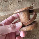 Spool shaped wooden object with a wooden ring around it.