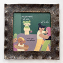A square ceramic frame with textured, speckled dark brown and black glaze. It frames a colorful illustration of characters dancing and standing on a green background, with text accompanying it.