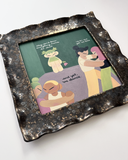 A square ceramic frame with textured, speckled dark brown and black glaze. It frames a colorful illustration of characters dancing and standing on a green background, with text accompanying it.