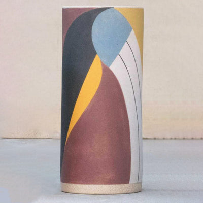 Ceramic vase without any curvature. It is painted in earth tones: burgundy, blue, white and yellow and consists of geometric shapes.