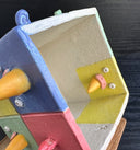 Ceramic cube made up of 8 different colored cubes: green, yellow, red and blue. Bird beaks come out of one side and little wings come out of other sides.