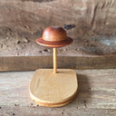 Wooden sculpture of smooth, UFO space craft on a wooden dowel attached to a wooden base.