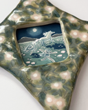 A ceramic star-shaped frame with a textured green and beige glazed border and a central square inset illustration depicting a moonlit scene with a horse and girls running alongside.