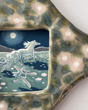 A ceramic star-shaped frame with a textured green and beige glazed border and a central square inset illustration depicting a moonlit scene with a horse and girls running alongside.