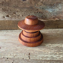 Wooden sculpture of a smooth UFO space craft, stacked over several wooden discs.