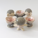 A circle of 6 ceramic figures, linked by their hands. 3 are small cartoon characters, the other 3 are flowers with arms.