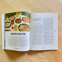 Open magazine spread featuring an illustration of a dinner table with each glass having eyes on it, accompanied by an article.