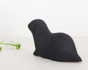 Wooden figurine of a black otter, seen from the back.