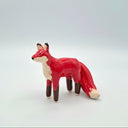 Red ceramic fox figurine on a light gray background