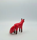 Red ceramic fox figurine on a light gray background