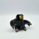 Black ceramic sculpture of a smoke monster with yellow eyes.