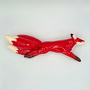 Red ceramic fox sculpture with several tails on a light gray background